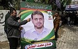 A picture taken on April 21, 2018 shows men holding up a poster portrait of 35-year-old Palestinian professor and Hamas member Fadi Mohammad al-Batsh who was killed in Malaysia, outside his family's house in Jabaliya in the northern Gaza Strip. (AFP/Mahmud Hams)