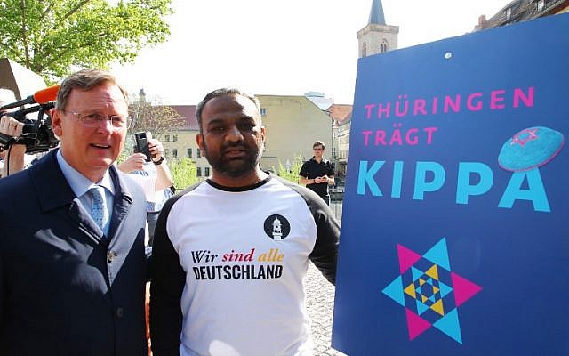 Thuringia's State Premier Bodo Ramelow (L) and Mailk Mohamed Suleman from the Muslim Ahmadiyya community pose next to an ad for the 'Thuringia wears kippa' rally in Erfurt, central Germany, on April 25, 2018. (AFP PHOTO / dpa / Bodo Schackow)