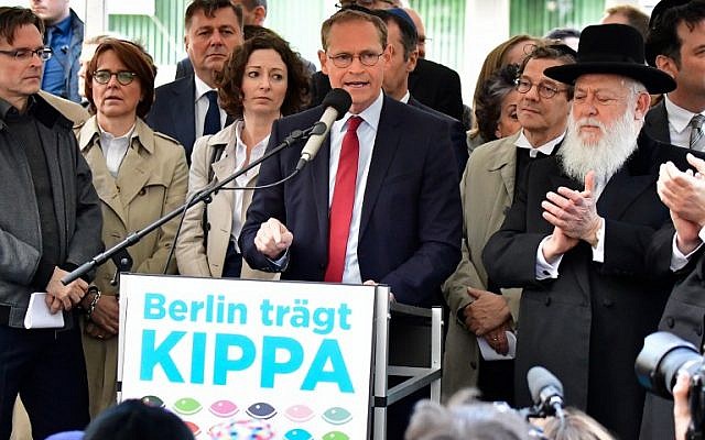 Berlin's mayor Michael Mueller (C) is applauded by Rabbi Yitshak Ehrenberg (R) during the "Berlin wears kippa" event, with more than 2,000 Jews and non-Jews wearing the traditional skullcap to show solidarity with Jews on April 25, 2018 in Berlin after Germany has been rocked by a series of anti-Semitic incidents. (AFP PHOTO / Tobias SCHWARZ)
