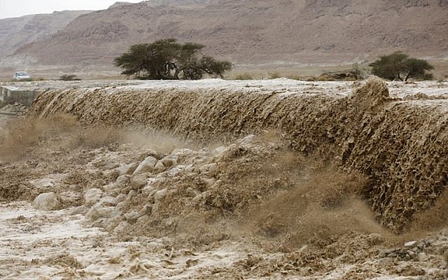 A general view of flooded water running through a valley blocking the main road along the Dead Sea, near the desert fortress of Masada, following heavy rainfall on April 25, 2018. (AFP Photo/Menahem Kahana)