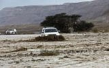 A car drives through flooded water running through a valley blocking the main road along the Dead Sea, near the desert fortress of Masada, following heavy rainfall on April 25, 2018. (AFP Photo/Menahem Kahana)