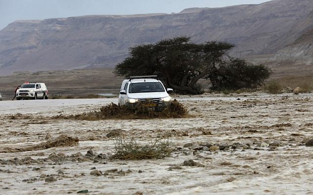 A car drives through flooded water running through a valley blocking the main road along the Dead Sea, near the desert fortress of Masada, following heavy rainfall on April 25, 2018. (AFP Photo/Menahem Kahana)