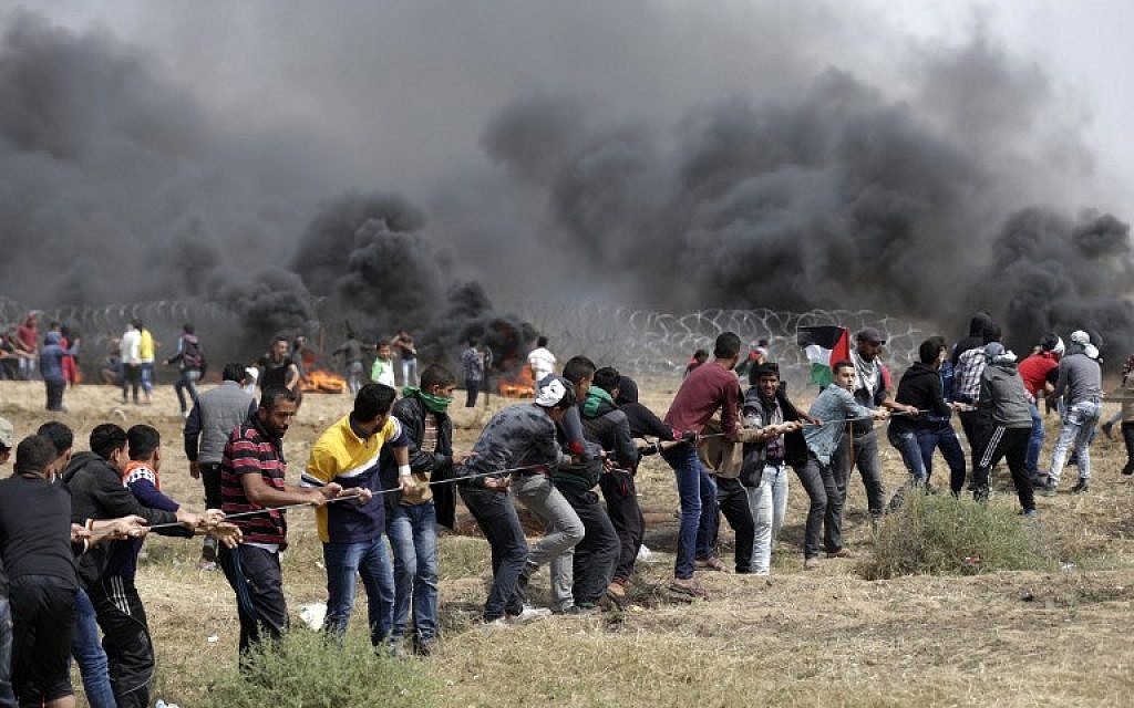 Palestinians try to pull down part of the border fence between Israel and Gaza east of Jabaliya in the northern Gaza Strip,  during the fifth straight Friday of mass riots along the border between Gaza and Israel, on April 27, 2018. (AFP Photo/Mahmud Hams)