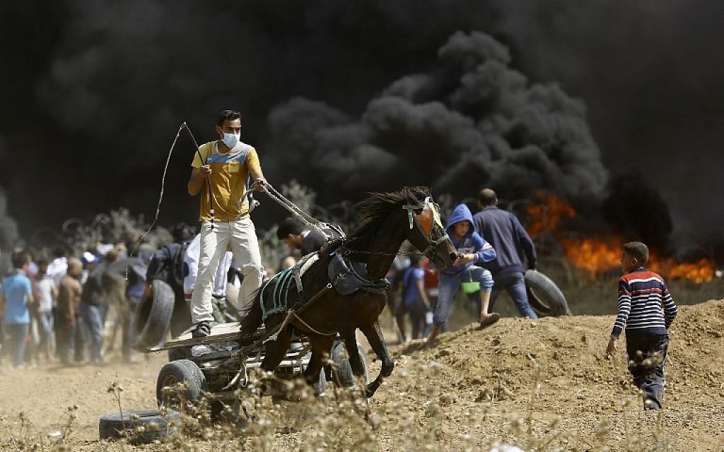 A Palestinian drives a horse-drawn cart during clashes with Israeli troops east of the Jabaliya in the northern Gaza Strip, on the fifth straight Friday of clashes along the border, on April 27, 2018 (AFP Photo/Mohammed Abed)
