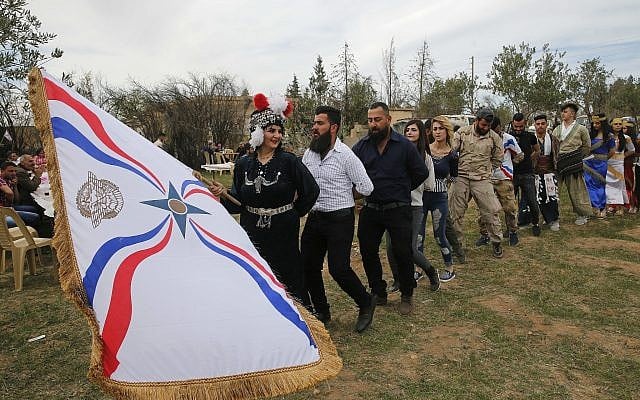 In this April 1, 2018 photo, Assyrian Christians wear traditional costumes and wave their flag, as they celebrate Easter and the Assyrian New Year, or Akitu, in the village of Tal Arboush, northern Syria. They were snatching joy out of a sober surrounding. (AP Photo/Hussein Malla) In this April 1, 2018 photo, Assyrian Christians wear traditional costumes and wave their flag, as they celebrate Easter and the Assyrian New Year, or Akitu, in the village of Tal Arboush, northern Syria. They were snatching joy out of a sober surrounding. (AP Photo/Hussein Malla)