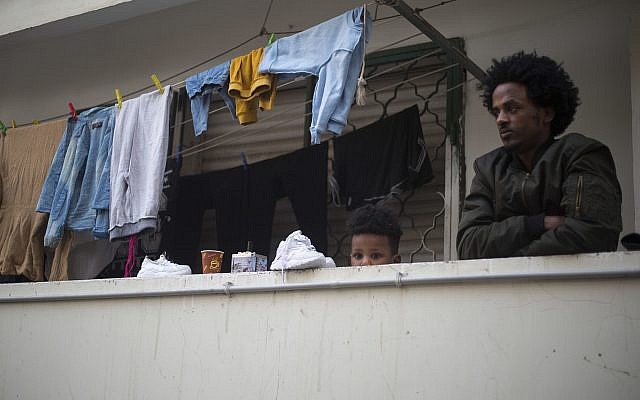 In this Tuesday, April 3, 2018 photo, an African migrant and his son look out of the balcony in southern Tel Aviv. (AP Photo/Ariel Schalit) In this Tuesday, April 3, 2018 photo, an African migrant and his son look out of the balcony in southern Tel Aviv. (AP Photo/Ariel Schalit)