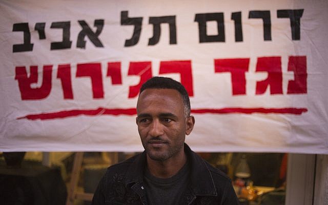 In this Tuesday, April 3, 2018 photo, Eritrean Halofom Sulta sits under a banner "South Tel Aviv against deportation" after speaking to the Associated Press in southern Tel Aviv. (AP Photo/Ariel Schalit) In this Tuesday, April 3, 2018 photo, Eritrean Halofom Sulta sits under a banner "South Tel Aviv against deportation" after speaking to the Associated Press in southern Tel Aviv. (AP Photo/Ariel Schalit)
