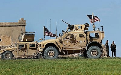 In this March 29, 2018 file photo, a fighter, second from right, of the US-backed Syrian Manbij Military Council is parked next to US humvee at a US troop outpost on a road leading to the tense front line between Syrian Manbij Military Council fighters and Turkish-backed fighters, at Halawanji village, north of Manbij town, Syria. (AP Photo/Hussein Malla, File)