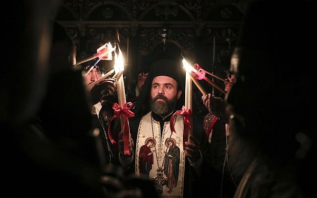 A Greek Orthodox priest lights candles of the faithful with Holy Fire brought from Jerusalem inside a church in Athens, Greece, on April 7, 2018. (AP Photo/Yorgos Karahalis)