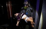 A rescue worker carrying a child following an alleged chemical weapons attack in the rebel-held town of Douma, near Damascus, Syria, on April 8, 2018. (Syrian Civil Defense White Helmets via AP, File)