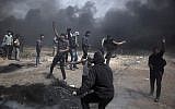 Palestinian protesters hurl stones at Israeli troops at the Gaza Strip's border with Israel, Friday, April 13, 2018. (AP Photo/ Khalil Hamra)