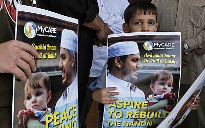 A kid holds a poster of Palestinian Fadi al-Batsh portrait at a mosque in Selayang, on the outskirt of Kuala Lumpur, Malaysia, Wednesday, April 25, 2018. (AP Photo/Sadiq Asyraf)
