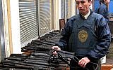 An officer stands by a large arms cache found by Chilean authorities at the commune-like Colonia Dignidad, or Dignity Colony, is displayed in Parral, Chile, some 410 kilometers (255 miles) south of Santiago, Wednesday, June, 15, 2005. (AP Photo)