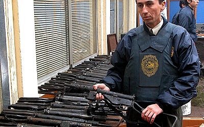 An officer stands by a large arms cache found by Chilean authorities at the commune-like Colonia Dignidad, or Dignity Colony, is displayed in Parral, Chile, some 410 kilometers (255 miles) south of Santiago, Wednesday, June, 15, 2005. (AP Photo)