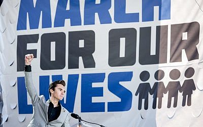 David Hogg, a survivor of the mass shooting at Marjory Stoneman Douglas High School in Parkland, Florida., raises his fist after speaking during the 'March for Our Lives' rally in support of gun control in Washington, Saturday, March 24, 2018 (AP Photo/Andrew Harnik)