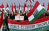 In this photo taken Thursday, March 15, 2018, Hungarian Prime Minister Viktor Orban sings along with performers wearing traditional outfits at the end of his speech outside the Hungarian Parliament building in Budapest, Hungary. (AP Photo/Darko Vojinovic)