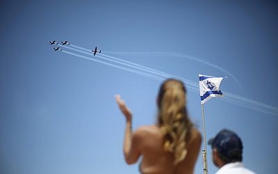 People watch as an Israeli acrobatic team fly over during Israel's 70th Independence Day celebrations, in Tel Aviv, Israel, Thursday, April 19, 2018. (AP Photo/Ariel Schalit)