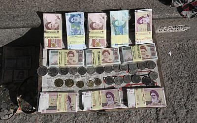 Illustrative photo of Iranian banknotes and foreign coins displayed by a vendor on a side walk of the Ferdowsi Street in Tehran, Iran, January 23, 2013. (Vahid Salemi/AP)