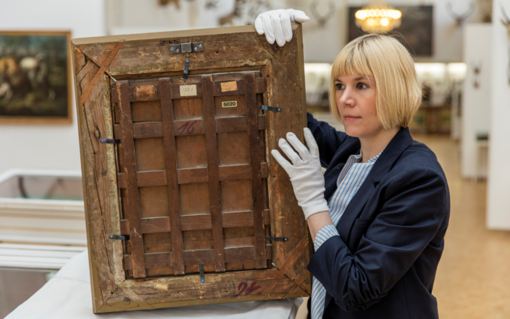 Carolin Lange inspecting the back/the frame of an oil painting. (Landesstelle für die nichtstaatlichen Museen in Bayern) Carolin Lange inspecting the back/the frame of an oil painting. (Landesstelle für die nichtstaatlichen Museen in Bayern)