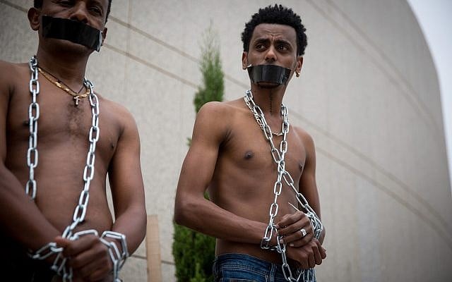 African asylum seekers set up a mock slave auction as part of a protest outside the Ministry of Defense in Tel Aviv, against their deportation, on April 3, 2018. (Miriam Alster/ Flash90) African asylum seekers set up a mock slave auction as part of a protest outside the Ministry of Defense in Tel Aviv, against their deportation, on April 3, 2018. (Miriam Alster/ Flash90)