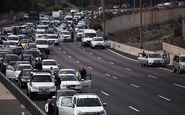 People stand still on the Ayalon highway in Tel Aviv as a two-minute siren is sounded across Israel to mark Holocaust Remembrance Day on April 12, 2018. (Miriam Alster/Flash90)