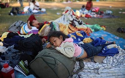 Nayeli Zelaya, from El Salvador, rests alongside her two sleeping siblings, at the sports club where Central American migrants traveling with the annual "Stations of the Cross" caravan are camped out in Mexico, April 4, 2018. (AP Photo/Felix Marquez)
