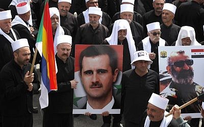 Druze residents of the Ein Qiniye village on the Israeli side of the Golan Heights hold pictures of the Syrian president Bashar Assad and Issam Zahreddine, the late Major General of the Syrian Republican Guard as they march during a rally marking Syria's Independence Day on April 17, 2018. (AFP PHOTO / JALAA MAREY)