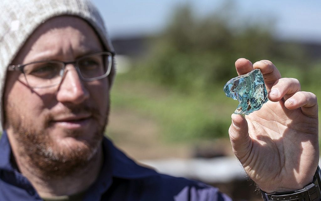 Archaeologist Yair Amitzur holding a chunk of glass discovered during preparations for the new Sanhedrin Trail in the Galilee. According to Amitzur, the find is evidence of the glass industry from the time of the Sanhedrin. (Yaniv Berman, Israel Antiquities Authorit)