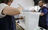 Lebanese election registrars break the seals open from a ballot box as their poll station opens to receive voters in the first parliamentary election in nine years, in the coastal city of Byblos, north of the capital Beirut, on May 6, 2018. (AFP/Joseph EID)