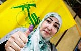 A Lebanese Shiite woman flashes her ink-stained thumb and waves a Hezbollah flag after voting at a polling station in the capital Beirut on May 6, 2018, as the country votes in the first parliamentary election in nine years. (AFP PHOTO / ANWAR AMRO)