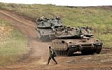 An Israeli soldier next to Merkava Mark IV tanks in the Golan Heights during a military drill on May 7, 2018. (AFP Photo/Jalaa Marey)