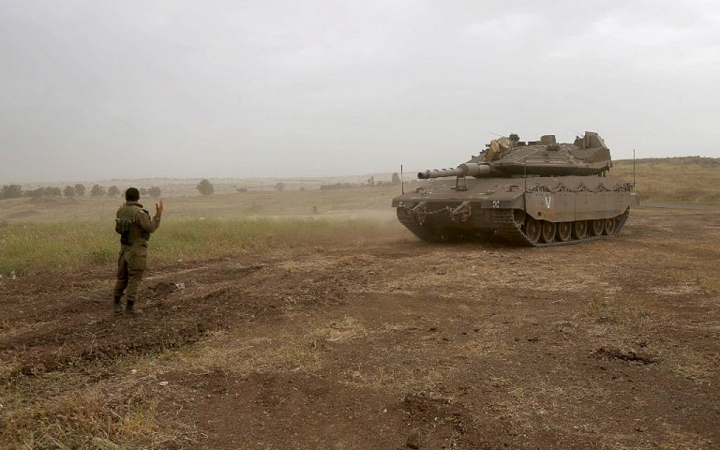 An Israeli soldier directs a Merkava Mark IV tank during a military exercise in the Golan Heights on May 7, 2018. (Jalaa Marey/AFP) An Israeli soldier directs a Merkava Mark IV tank during a military exercise in the Golan Heights on May 7, 2018. (Jalaa Marey/AFP)