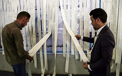 Iraqi electoral commission employees examine electronic counting machine print-outs in the holy city of Najaf on May 13, 2018, for the special round of voting that took place for the police and military on May 10 in the country's first parliamentary election since declaring victory over the Islamic State terror group. (AFP Photo/Haidar Hamdani)