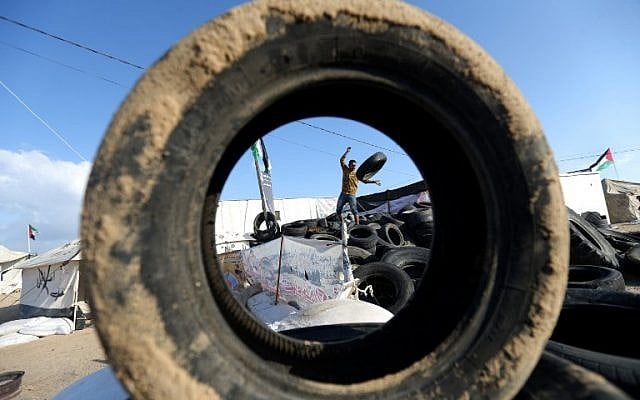 A man carries tires to be burnt as Palestinians prepare to demonstrate along the Gaza-Israel border, May 14, 2018. (AFP PHOTO/MOHAMMED ABED_ A man carries tires to be burnt as Palestinians prepare to demonstrate along the Gaza-Israel border, May 14, 2018. (AFP PHOTO/MOHAMMED ABED_