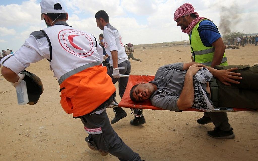 Palestinians carry a protester injured during clashes along the Gaza-Israel border, east of Khan Yunis,  May 14, 2018. (AFP Photo/Said Kahtib)