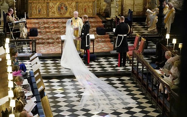 Britain's Prince Harry, Duke of Sussex (R) and US actress Meghan Markle (L) stand facing each other hand-in-hand before Archbishop of Canterbury Justin Welby (C) during their wedding ceremony in St George's Chapel, Windsor Castle, in Windsor, on May 19, 2018. (AFP PHOTO / POOL / Owen Humphreys)