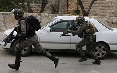 Israeli troops run during clashes with Palestinian youth in the al-Amari refugee camp near Ramallah in the West Bank after they stormed the camp on May 28, 2018. ( AFP PHOTO / ABBAS MOMANI)