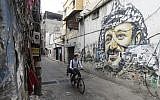 Mohammed, a Lebanese roaming barber, better known as 'Abo Tawila,' rides his bicycle in a street on the outskirts of the Palestinian refugee camp Burj al-Barajneh, south of the capital Beirut on May 29, 2018. (AFP PHOTO / JOSEPH EID)
