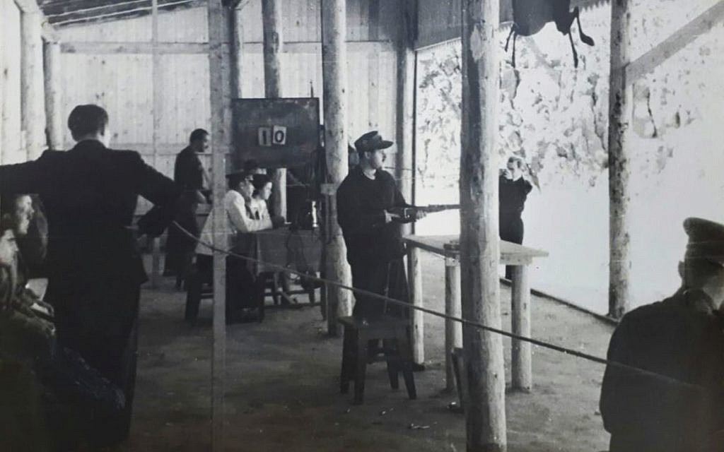 Joseph Schneider holds a rifle in a shooting course. (Courtesy National Library of Israel)