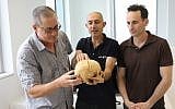 Researchers who are studying the first evidence of blood vengeance, discovered in a cave in the Jerusalem Hills. From left to right: Prof. Boaz Zissu Dr. Yossi Nagar and Dr. Haim Cohen with the skull (Chen Galili/Israel Antiquities Authority)