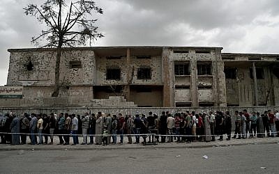 Iraqis wait in a long line to cast their vote in the country's parliamentary elections at a polling site in a battle-damaged building in west Mosul, Iraq, Saturday, May 12, 2018.(AP/Maya Alleruzzo)