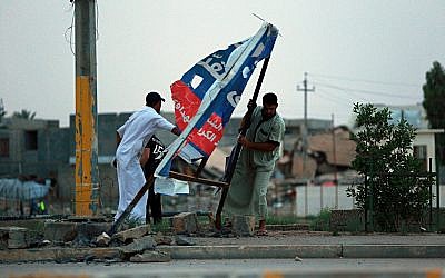 In this photo from May 12, 2018, people dismantle campaign posters for parliamentary candidates in Ramadi, Iraq. The vote Saturday saw a record low turnout, with 44 percent of eligible voters casting ballots. (AP Photo/Hadi Mizban)