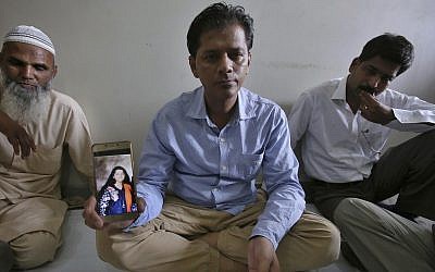 Abdul Aziz Sheikh, center, father of Sabika Sheikh, a victim of a shooting at a Texas high school, shows a picture of his daughter in Karachi, Pakistan, Saturday, May 19, 2018. (AP Photo/Fareed Khan)