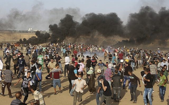Amid black smoke from burning tires, Palestinian protesters run from teargas fired by Israeli troops during a protest at the Gaza Strip's border with Israel, Friday, May 11, 2018. (AP Photo/Adel Hana) Amid black smoke from burning tires, Palestinian protesters run from teargas fired by Israeli troops during a protest at the Gaza Strip's border with Israel, Friday, May 11, 2018. (AP Photo/Adel Hana)