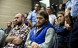 Kosovo police officers stand guard next to from left, Kenan Plakaj, Arton Ahmeti, center, and Leotrim Musliu, second row right, in court for the foiled attack against the Israeli team in a 2016 qualifying World Cup match in neighboring Albania, in Kosovo's capital Pristina on Friday, May 18, 2018. (AP Photo/Visar Kryeziu)