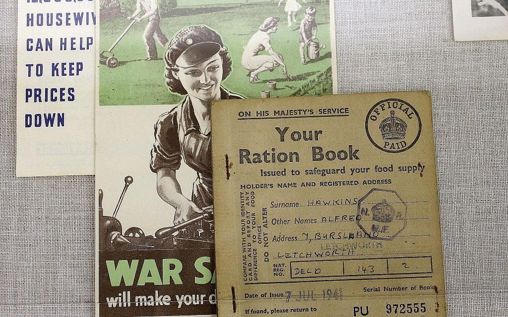In this Monday, May 21, 2018, photo, a World War II British ration card, right, rests on a flyer, center, that shows a woman operating machinery juxtaposed with a depiction of a family doing yard work, in a display at The International World War II Museum, in Natick, Mass. (AP Photo/Steven Senne)