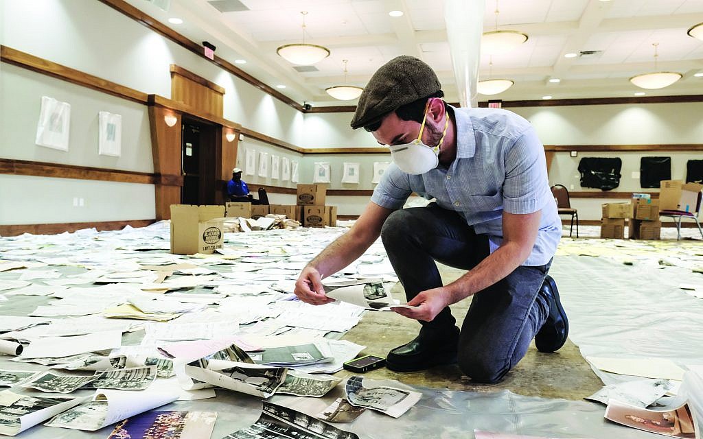 Dr. Joshua Furman examines historical photographs impacted by flooding at Congregation Beth Yeshurun. (Courtesy: Michael C. Duke/Jewish Herald-Voice)