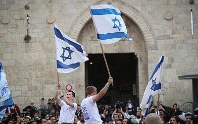 Thousands of Jewish marchers wave the Israeli flags as they celebrate Jerusalem Day by dancing through Damascus Gate on their way to the Western Wall in the Old City of Jerusalem, May 13, 2018. (Yonatan Sindel/Flash90)