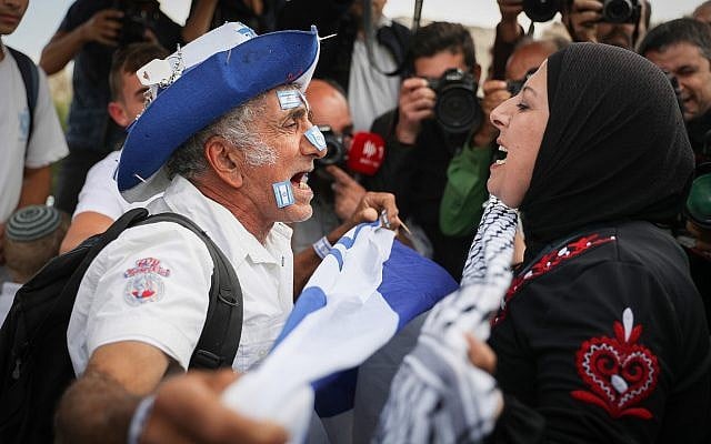 A Jewish man waving the Israeli flag argues with an Arab woman as thousands celebrate Jerusalem Day by dancing through Damascus Gate on their way to the Western Wall in the Old City of Jerusalem, May 13, 2018. (Yonatan Sindel/Flash90)