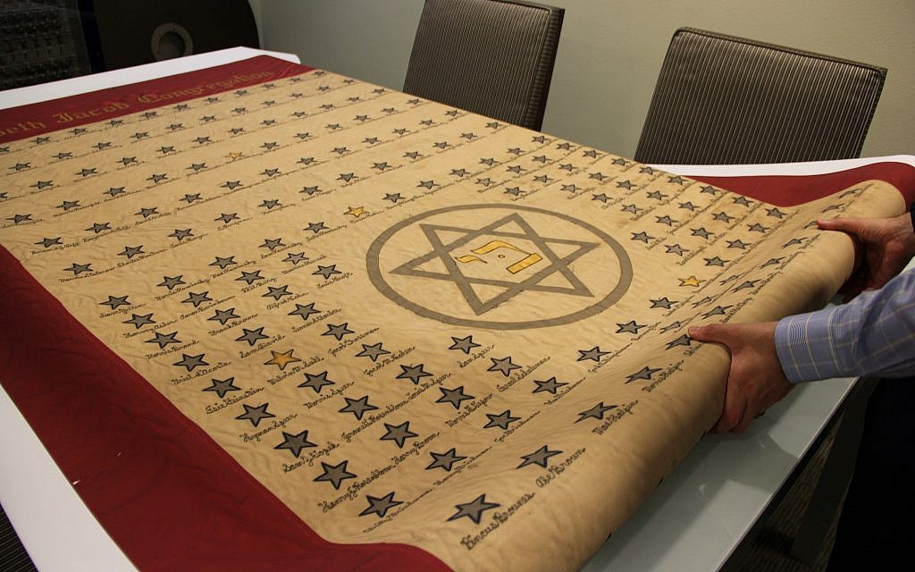 Dr. Josh Furman unfolding a copy of a 1940's banner from the Beth Jacob Synagogue honoring Jewish veterans from the Houston area who served in World War II. (Tracy Frydberg/Hurricane Harvey)
